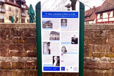Infotafel „75 Jahre jüdisches Leben in Lohr“ mit historischen Fotos und Texten vor einer Sandsteinmauer