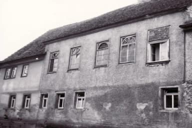 Historische Hausfassade mit Sprossenfenstern und abblätterndem Putz, Schwarzweißaufnahme