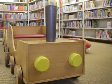 Kinderspielzug aus Holz in einer Bibliothek zwischen Bücherregalen