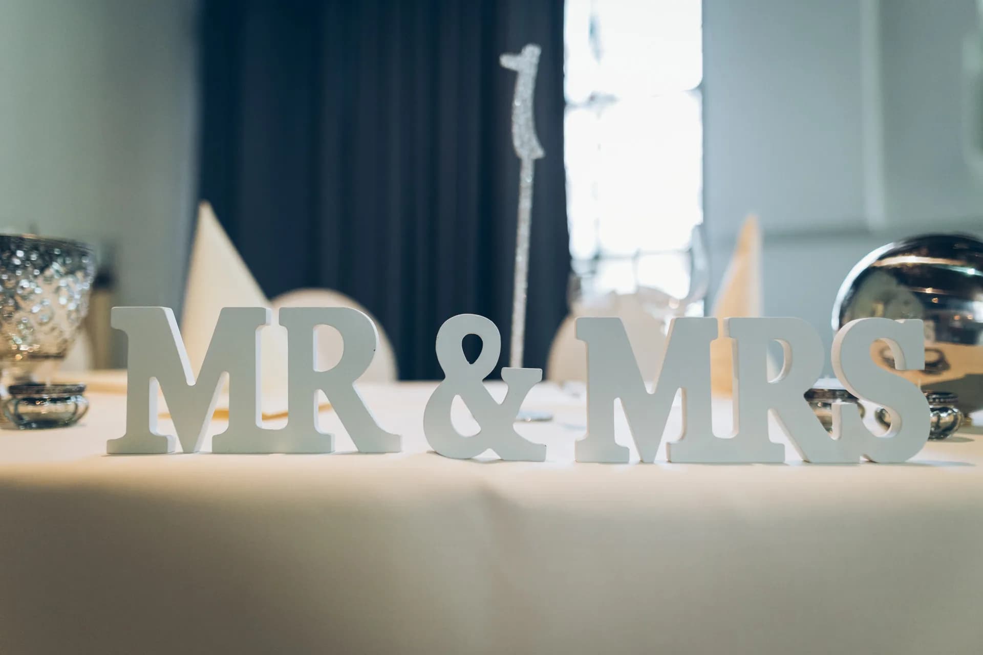 Dekobuchstaben „Mr & Mrs“ auf einem weiß gedeckten Tisch bei einer Hochzeitsfeier