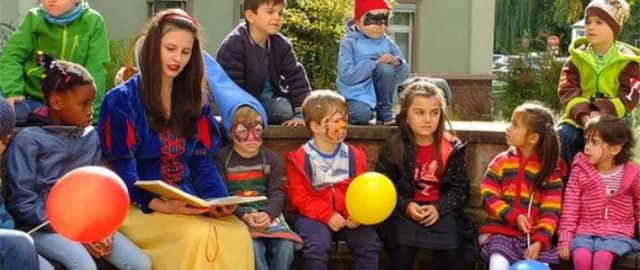 Das Lohrer Schneewittchen liest Kindern mit Luftballons und geschminkten Gesichtern aus einem Märchenbuch mit Erzählungen der Brüder Grimm vor.