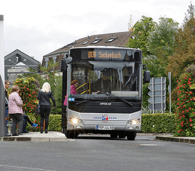 Mehrere Menschen laufen auf einen Bus zu, der gerade an einer Haltestelle in Lohr am Main hält.