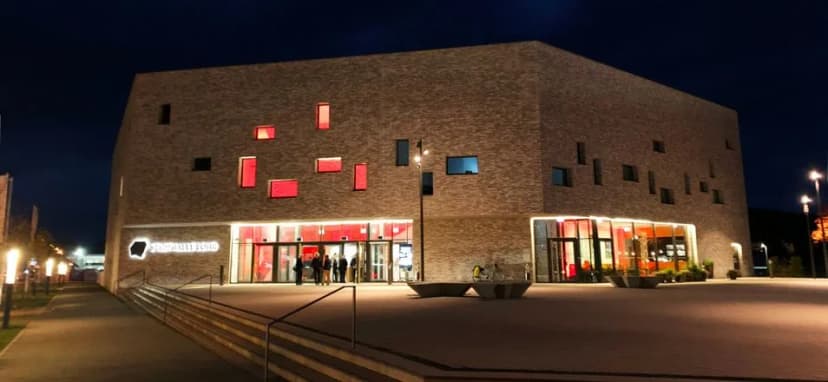 Stadthalle Lohr bei Nacht mit beleuchteten roten Fensterelementen und Eingangsbereich