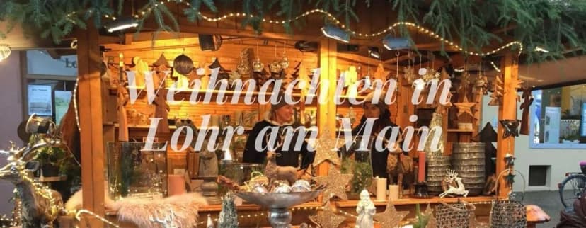 Beleuchteter Weihnachtsmarktstand mit Holzdekoration, Sternen und Figuren, Schriftzug Weihnachten in Lohr am Main