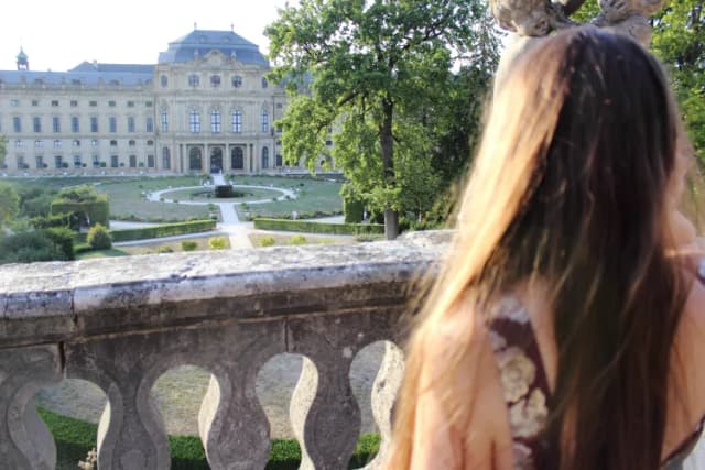 Eine Frau ist von hinten zu sehen und blickt auf die Residenz in Würzburg