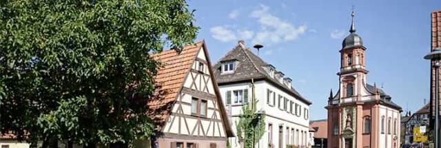 Fachwerkhäuser und Kirchturm mit Zwiebelhaube unter blauem Himmel im Ortskern