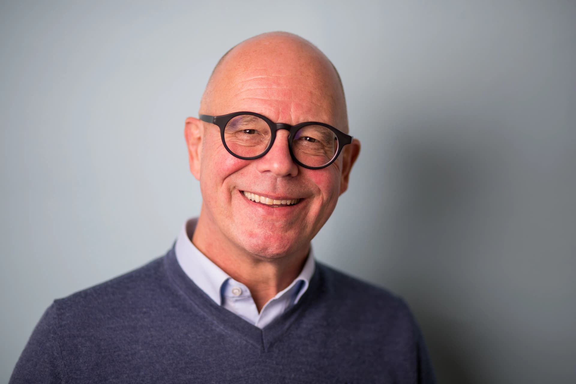 Porträt von Eric Schürr, lächelnder Mann mit Brille und dunklem Pullover