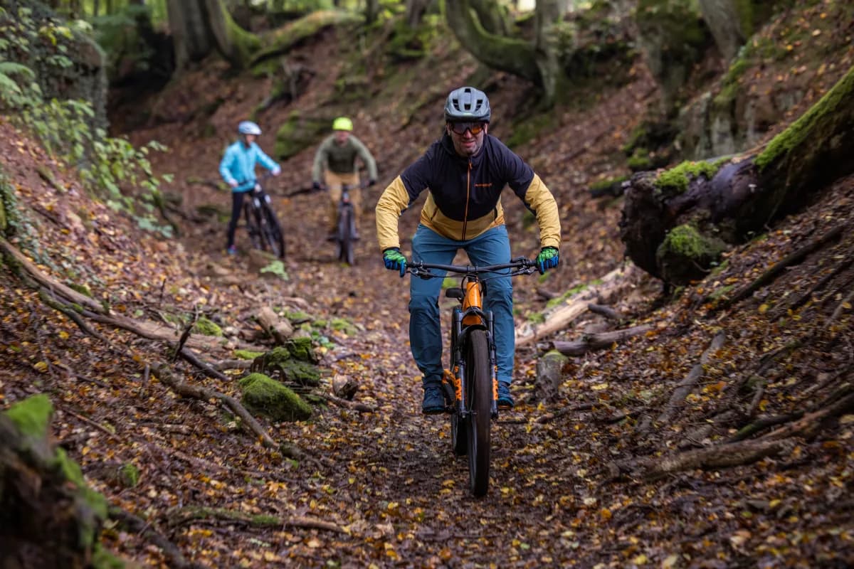 Ein Mountainbiker fährt durch den Bikewald Spessart. Im Hintergrund sind noch zwei weitere Mountainbiker zu sehen.