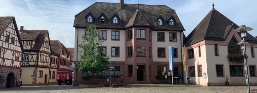 Historisches Rathausgebäude mit Fachwerkhäusern und gepflasterter Marktplatz im Vordergrund