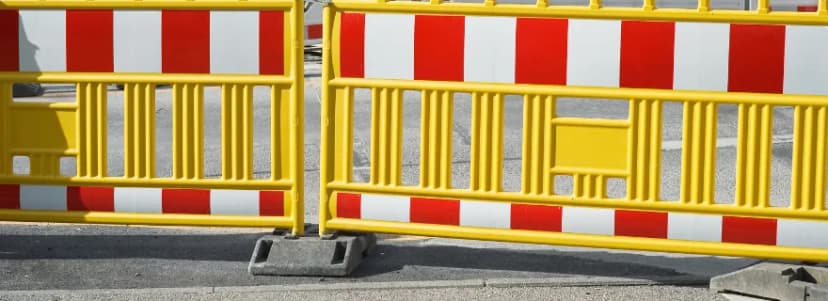 Gelbe Absperrgitter mit roten und weißen Streifen auf einer Straße
