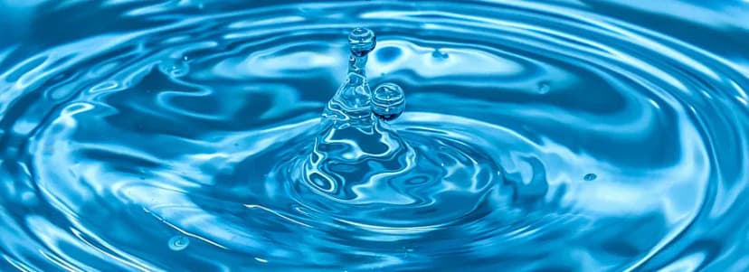 Wassertropfen erzeugt konzentrische Wellenringe auf blauer Wasseroberfläche