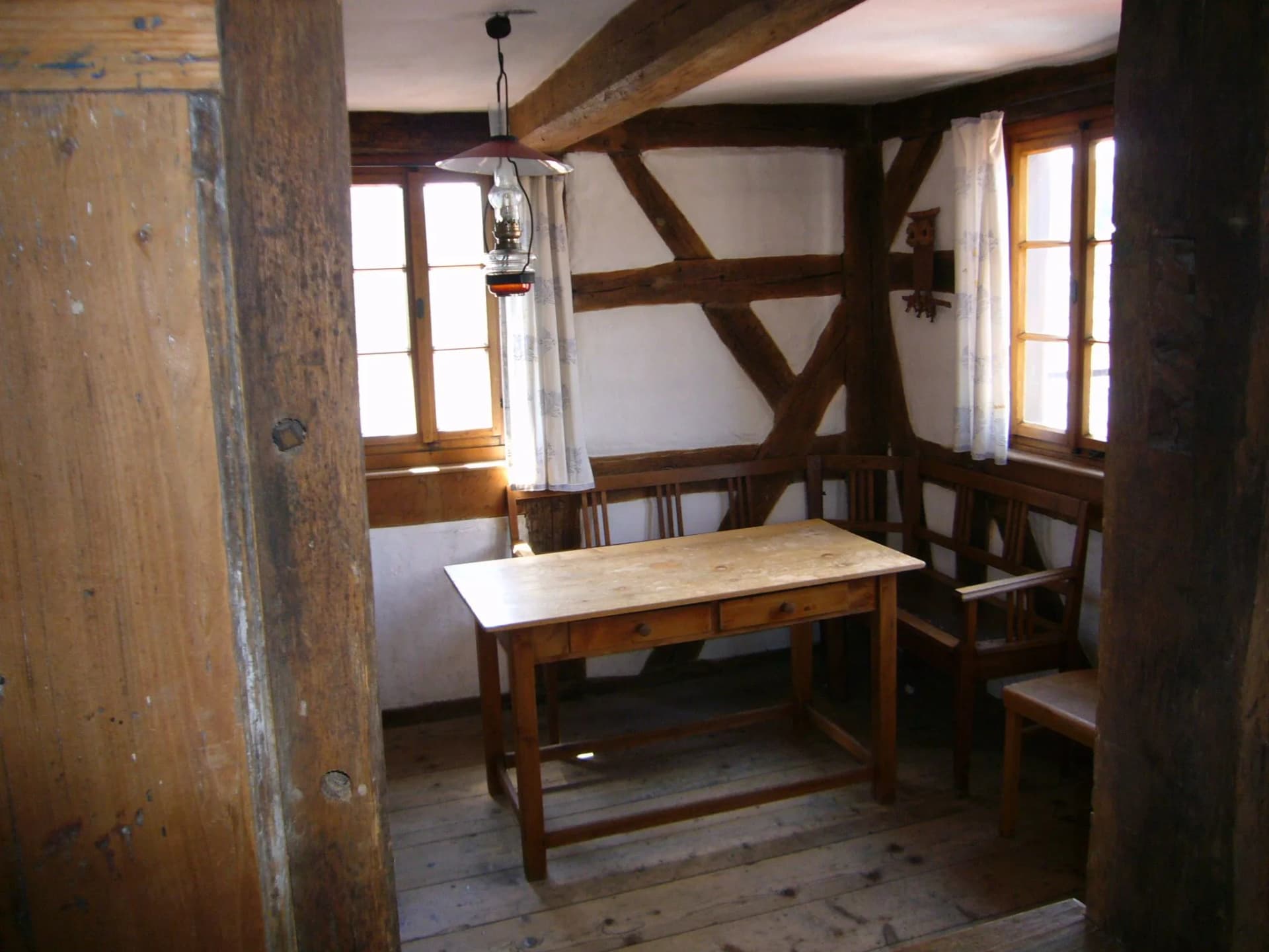 Historische Fachwerkstube mit Holztisch, Eckbank und hängender Petroleumlampe