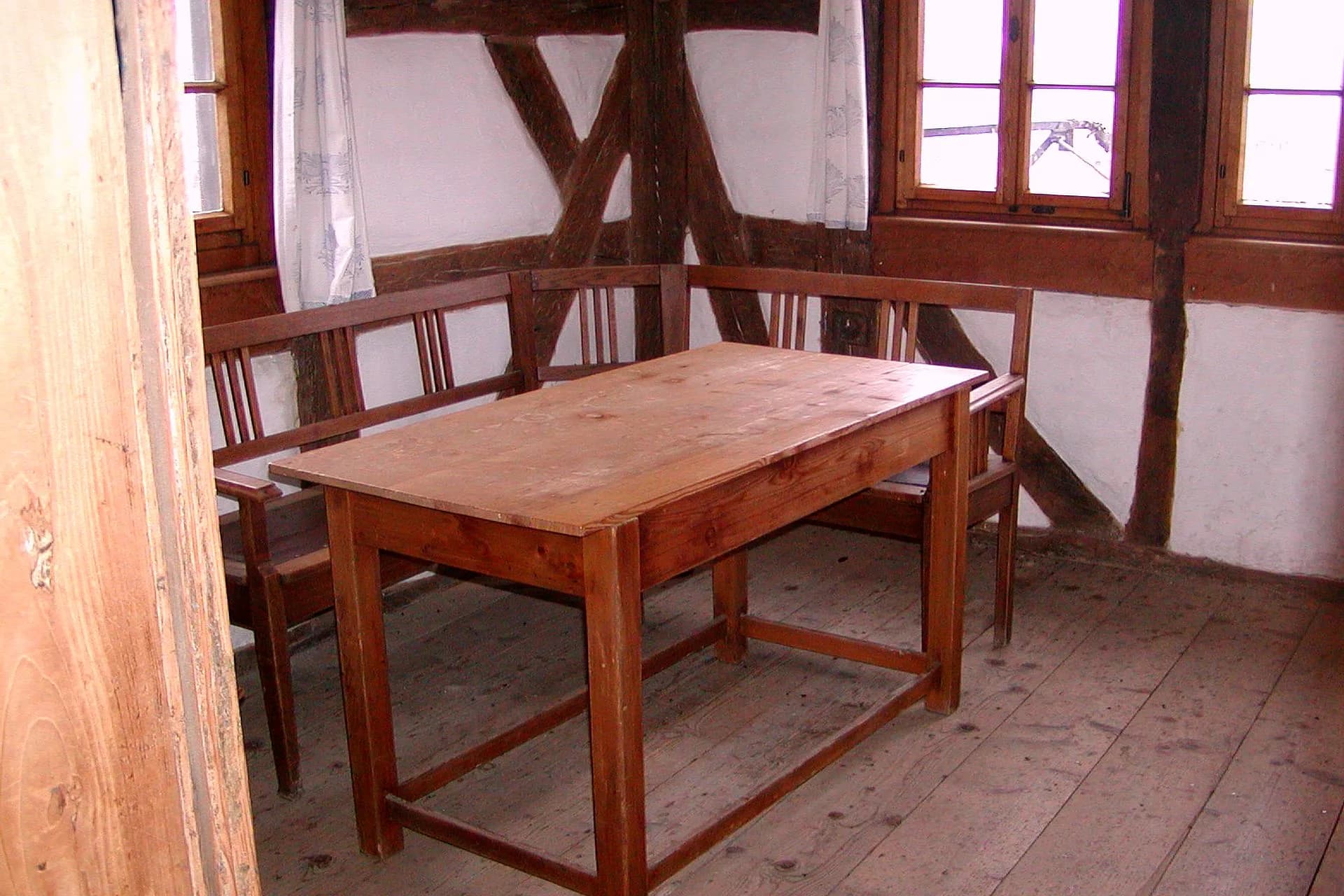 Holztisch mit Eckbank in einem Fachwerkraum mit Sprossenfenstern
