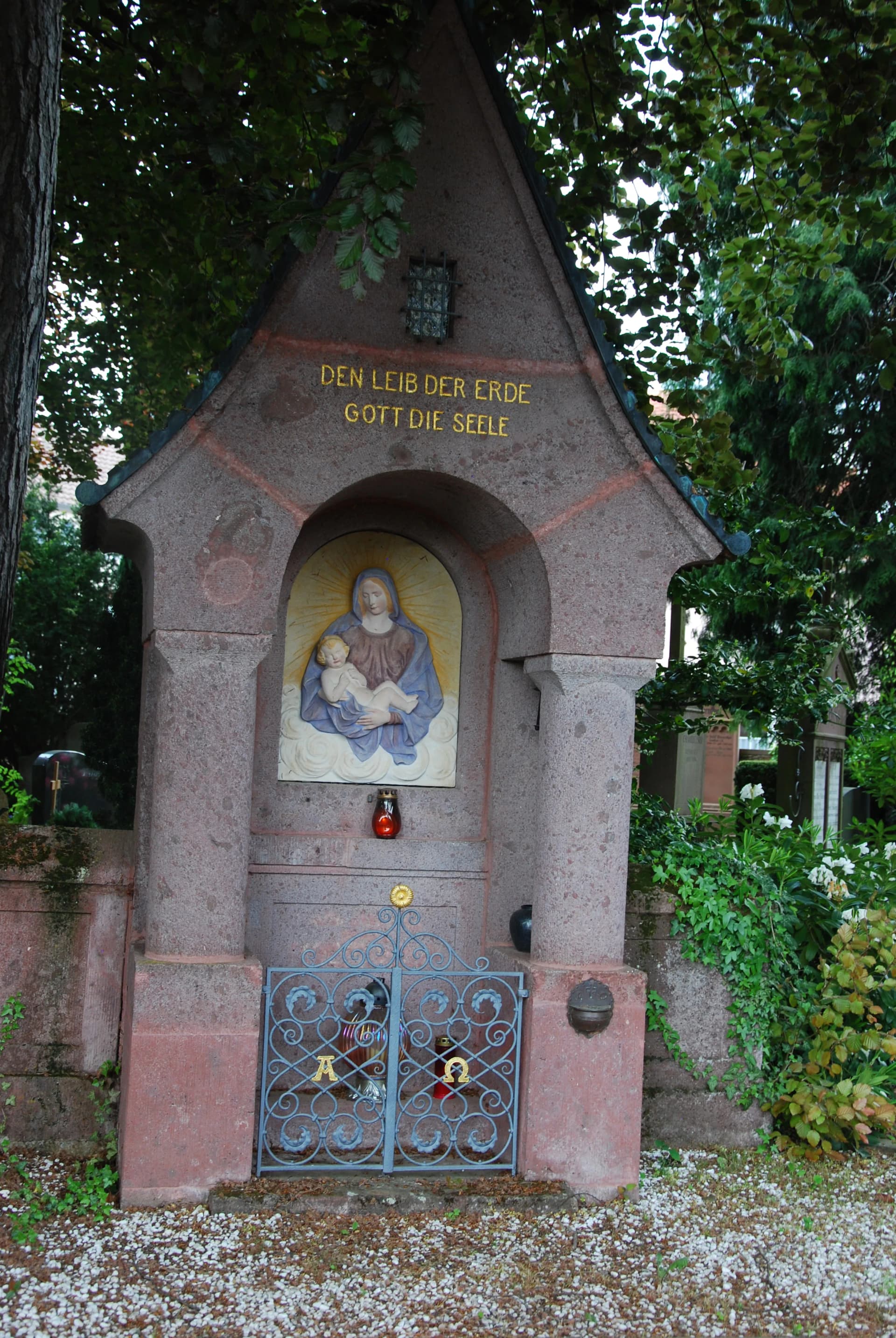 Steinerner Bildstock mit religiösem Motiv einer Heiligen und der Inschrift 'Den Leib der Erde Gott die Seele'