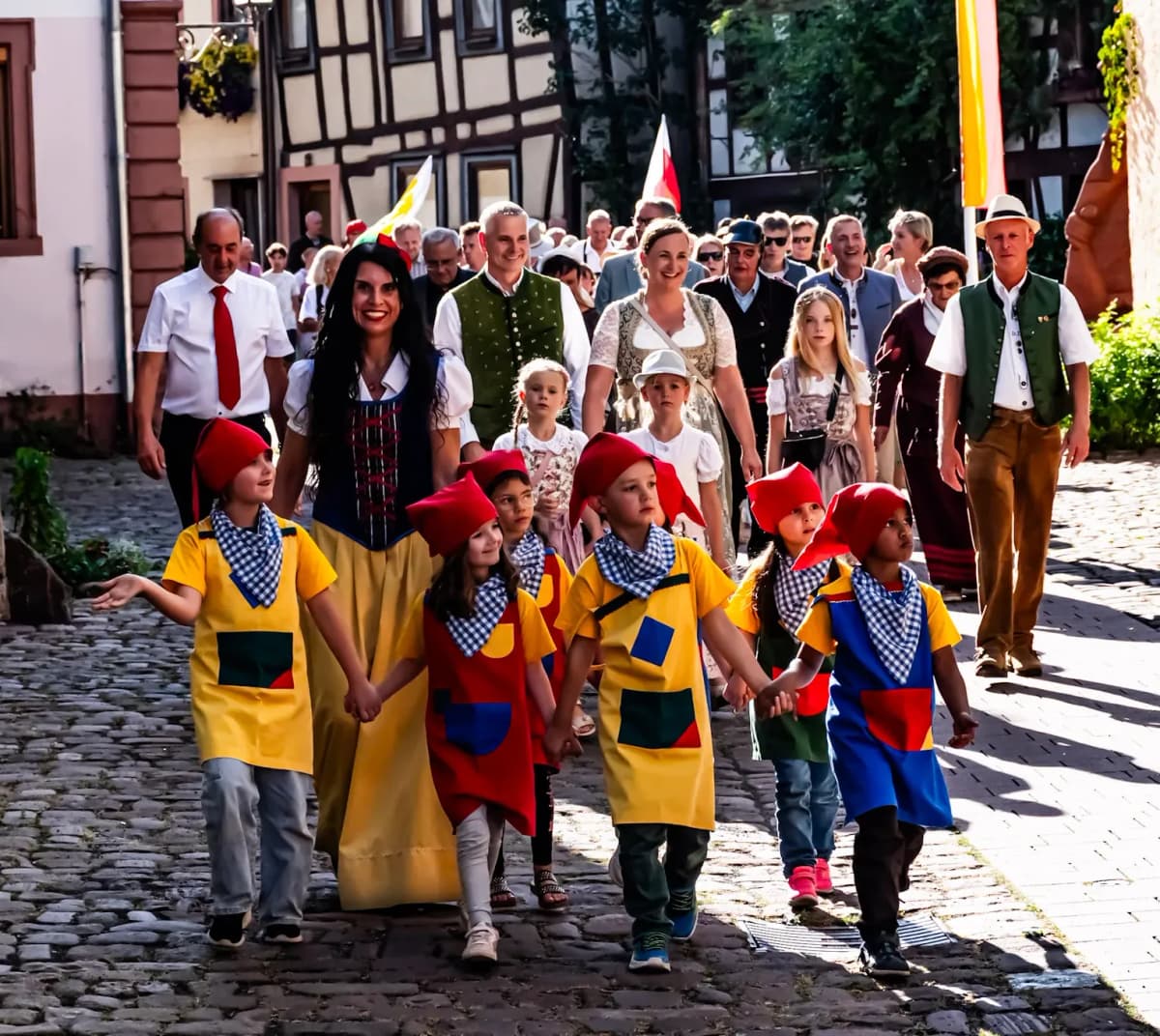 Schneewittchen und ihre sieben Zwerge, die jeweils rote Mützen tragen, laufen vor dem Bürgermeister der Stadt Lohr und Einwohnerinnen der Stadt beim Festumzug der Spessartfestwoche