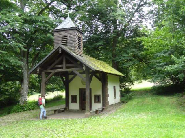 Blick auf die Gertraudenkapelle. Davor steht ein Wanderer.