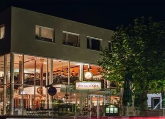 Brauhaus mit beleuchteter Glasfassade und Kupferkesseln bei Nacht