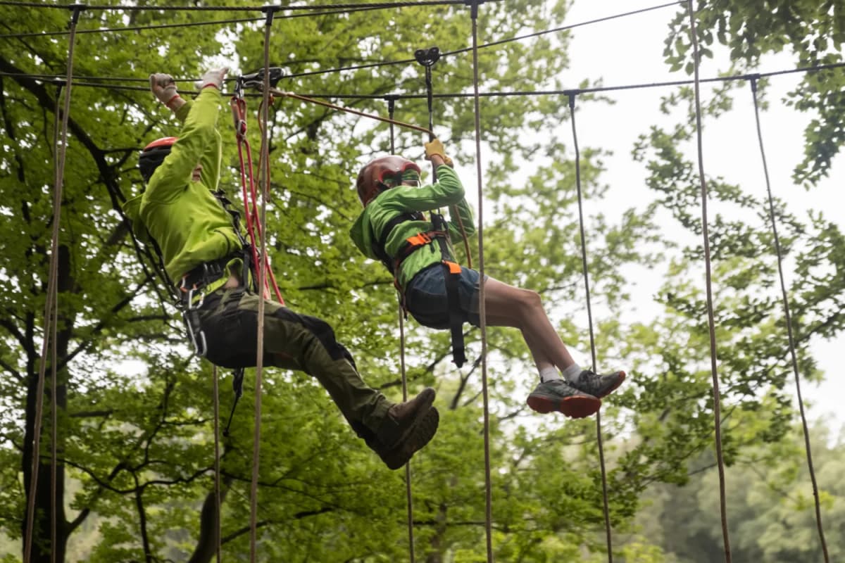 Zwei Kletterer die sich an einem Seil im Kletterwald in Heigenbrücken entlanghangeln
