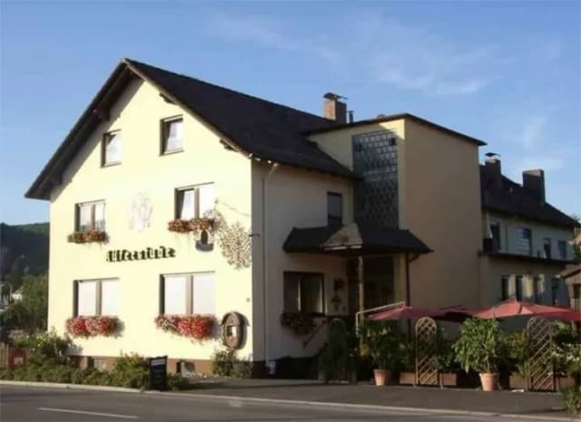 Gasthaus Küferstube mit gelber Fassade, Blumenkästen an den Fenstern und Terrasse mit Sonnenschirmen