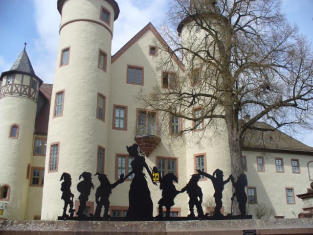 Silhouette von Schneewittchen und ihre sieben Zwerge vor dem Lohrer Schloss.