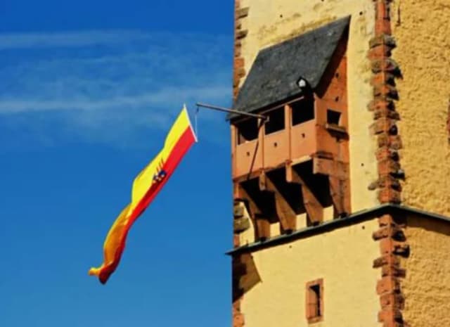 Gelb-rote Fahne im Wind an einem Turm mit Erker, dem Bayersturm