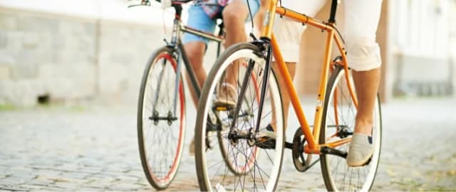 Zwei Radfahrer auf Fahrrädern fahren über ein Kopfsteinpflaster.