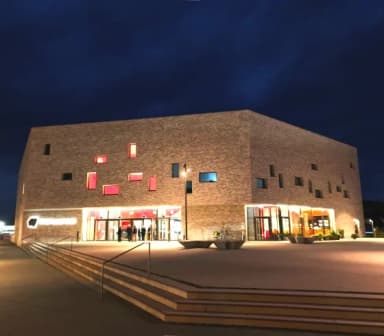 Blick auf die beleuchtete Stadthalle in Lohr am Main bei Nacht.