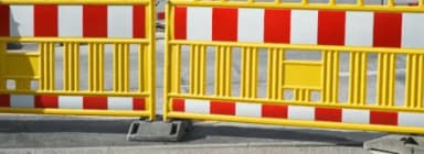 Gelbe Absperrschranken mit rot-weißen Warnstreifen auf einer Straße