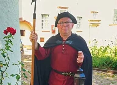 Mann in historischem Nachtwächter-Kostüm mit Hellebarde und Laterne vor einem Gebäude