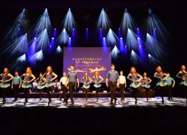 Tanzgruppe der Danceperados of Ireland in traditioneller Kleidung auf beleuchteter Bühne beim irischen Stepptanz.