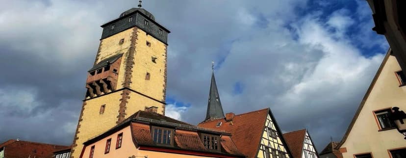 Bayersturm mit Fachwerkhäusern und Kirchturmspitze unter bewölktem Himmel in der Lohrer Altstadt