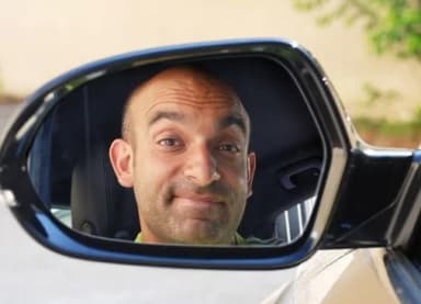 Gesicht eines Mannes spiegelt sich im Außenspiegel eines Autos