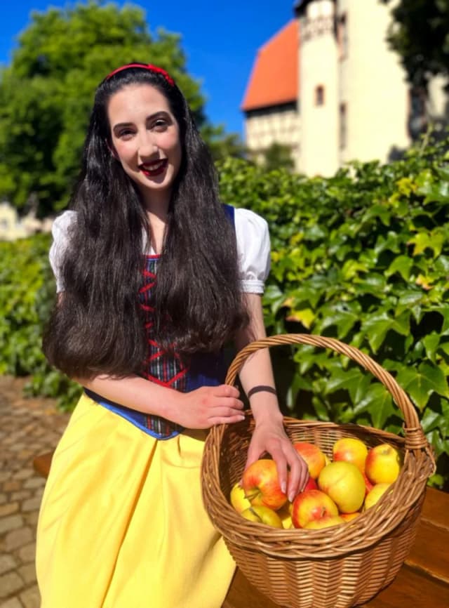 Das Lohrer Schneewittchen steht mit einem Apfelkorb vor dem Lohrer Schloss.