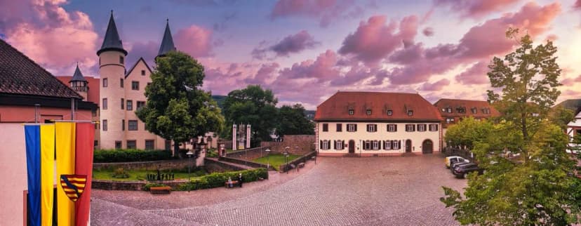 Schlossplatz mit Türmen des Lohrer Schlosses und historischen Gebäuden bei Abenddämmerung mit rosa Wolkenhimmel