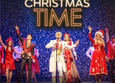 Sängerinnen und Sänger in weihnachtlichen Kostümen auf einer Bühne vor der Aufschrift „Christmas Time“.
