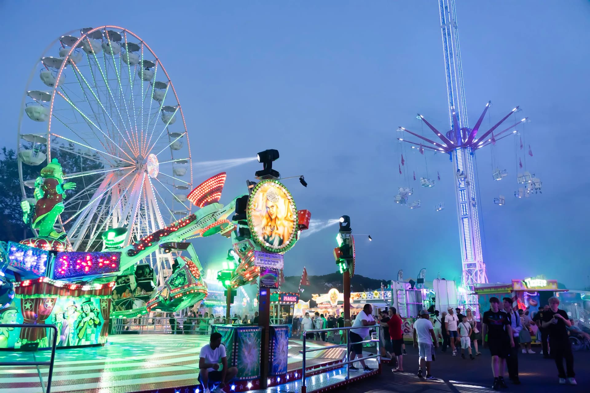 Blick auf mehrere Fahrgeschäfte der Lohrer Spessartfestwoche, unter anderem Riesenrad und Breakdance, am Abend.
