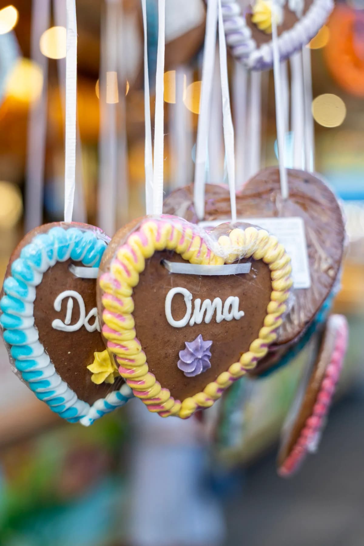 Lebkuchenherzen mit unterschiedlichen Beschriftungen, die an einem Stand hängen. Prominent ist ein Herz mit dem Schriftzug Oma zu sehen.