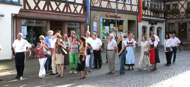 Besuchergruppe steht in einer Reihe vor Fachwerkhäusern in der Altstadt bei einer Stadtführung.