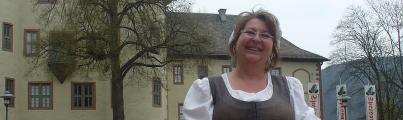 Eine Frau steht in historischer Kleidung, die ein Waschweib darstellt, mit Waschbrett und Korb vor dem Schloss in Lohr.